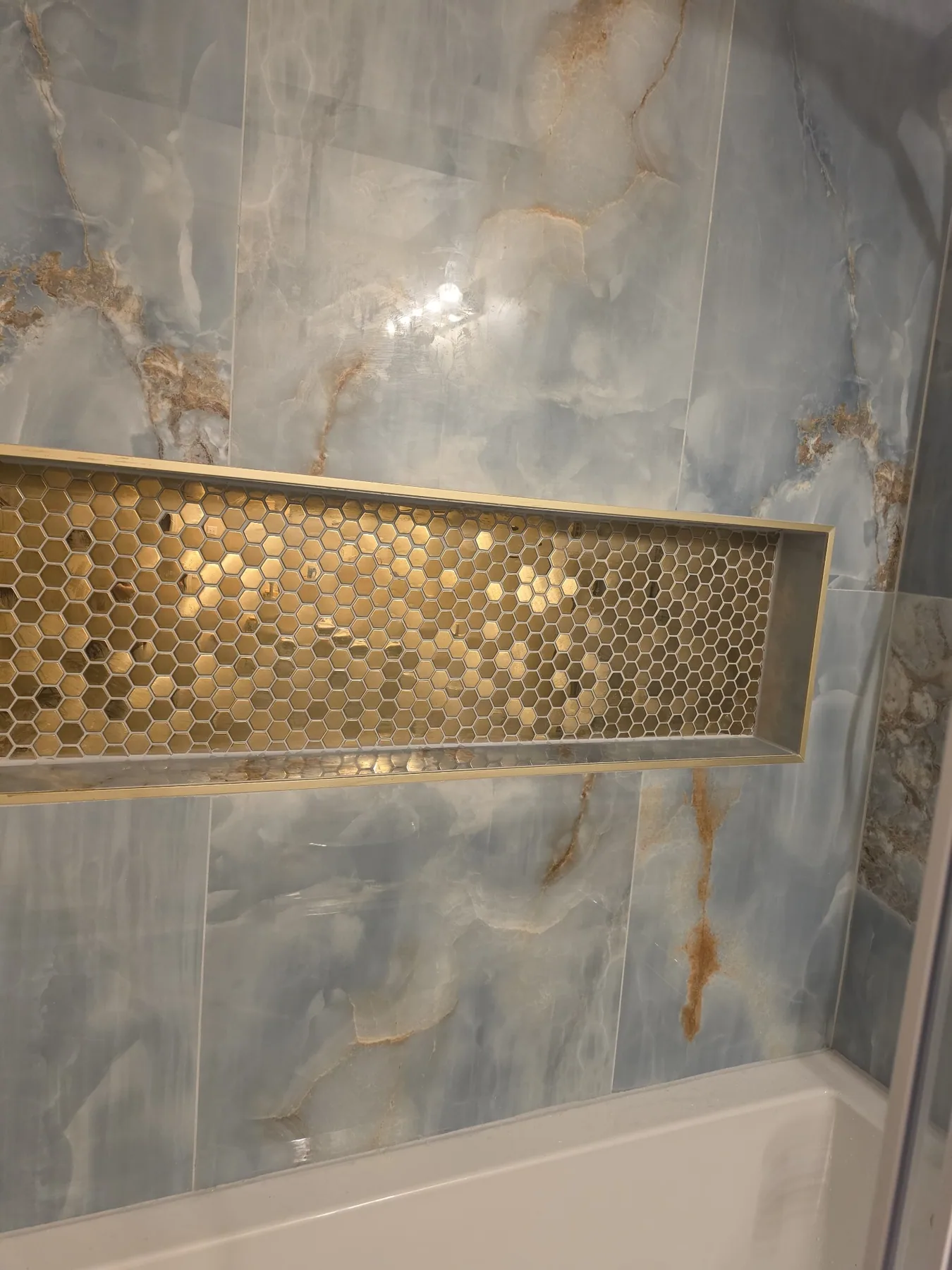 Remodeled shower with blue tile and gold mosaic niche